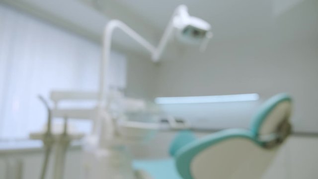 Blurred modern dental practice. Dental chair and other accessories used by dentists in blue, medic light