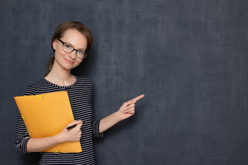 Portrait of happy cheerful girl holding folder, pointing at copy space