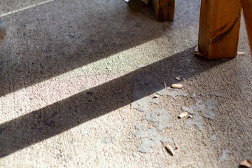 Concrete floor outdoors next to wooden bench legs with shadows