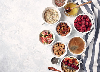 Obraz na płótnie Canvas Ingredients for a healthy breakfast, oatmeal with raspberries, figs, pecans, almonds, flax seeds, chia seeds with honey and coffee. Good morning, health concept. Top view