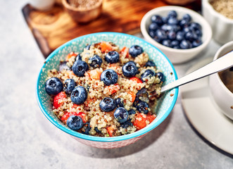 healthy breakfast, quinoa porridge with blueberries, nuts, seeds and superfoods