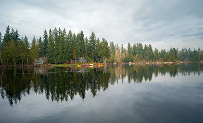 Lovely Lake Joy and the waterfront houses on a fog covered day with the surrounding trees and lingering clouds above reflecting in the water in the pacific northwest.