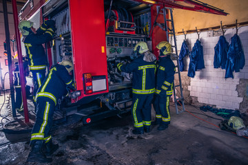 Group of firefighters preparing and inspecting pressure and water in the fire truck inside the fire station