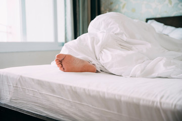 Close up of Human feet on a bed while sleeping in a bright room 