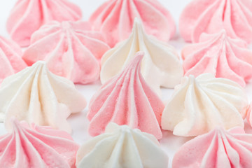 Small appetizing white and pink marshmallows shot on macro with selected focus on a white background in studio.