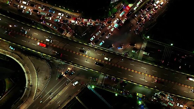 JAKARTA, Indonesia - December 18, 2019: Top down view of intersection road with night traffic in rush hour. Shot in 4k resolution from a drone flying from right to left
