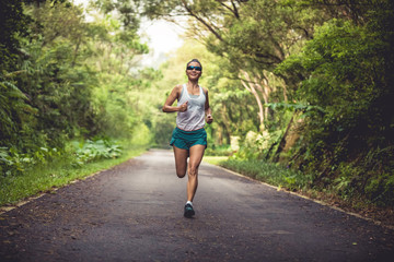 Female runner running at summer park trail . Healthy fitness woman jogging outdoors.