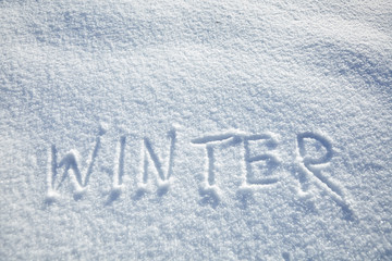 Winter background, inscription winter on snowy surface, natural snow texture with copy space, text, hand lettering