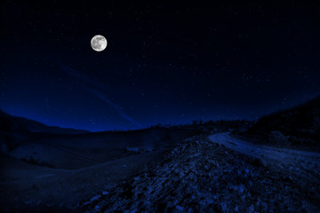 Fototapeta na wymiar Long exposure shot. Mountain Road through the forest on a full moon night. Scenic night landscape of dark blue sky with moon. Azerbaijan