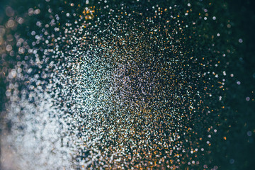Dark blinking background with golden and silver color glitter. Shining flare blurred bokeh texture.