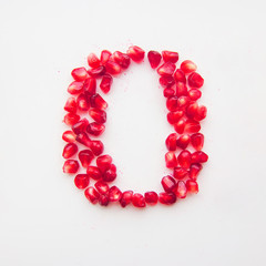 letter O folded from pomegranate berries on a white background top view