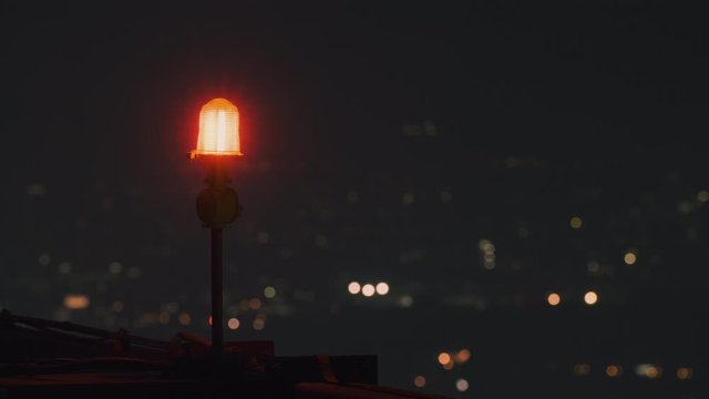 Indicator red light blink on the top of high building tower and business building light background for Safety zone. Signal warning light for the aircraft and plane