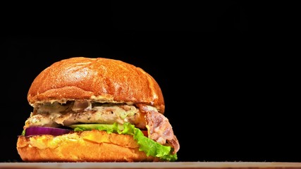 Craft burger is cooking on black background. Consist: sauce, lettuce, tomato, red onion, cucumber,...