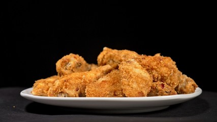 Cool beautiful fresh juicy cooked chicken wings in breading. Buffalo wings spread on food white plate in table. Very tasty and beautiful. Cooking with deep fryer fry machine.