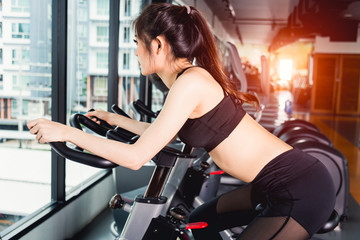 Fototapeta na wymiar Woman lifestyle using equipment exercise bike for training cardio workout