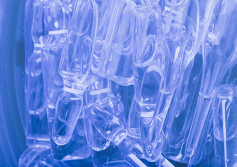 Glass medical ampoule vial for injection. Medicine is liquid sodium chloride with of aqueous solution in ampulla. Close up. Bottles ampule multicolor on background color and water. Human plasma.