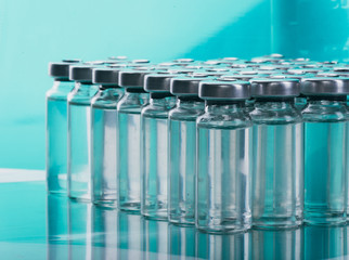 Glass medical ampoule vial for injection. Medicine is liquid sodium chloride with of aqueous solution in ampulla. Close up. Bottles ampule multicolor on background color and water. Human plasma.