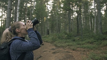 Traveler photographing scenic view in forest. One caucasian woman shooting nice magic look. Girl take photo video on dslr mirrorless camera. Professional photographer travel with backpack. Outdoor.