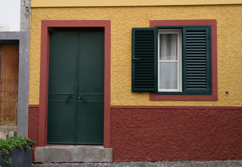 Artistically painted door on the  street where many entrances were decorated by various artists. Dark grey door, yellowish wall and burgundy red basement.