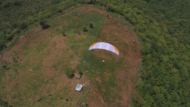Amazing aerial video of flying paraglider on the background of wild nature. Paraplan drifting above the green tropical trees. Extreme sport. Hipster modern hobby concept. Paraplane flying in the sky.