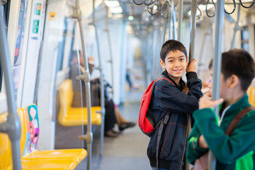 Little boy buying electric ticket and walking in the public sky train station with family