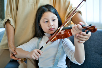 Asian kid learning and practising  to play violin at home © Songkhla Studio