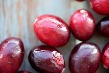 Macro view on group of bright glossy red cranberries on wooden surface