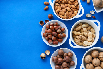 Various nuts in white bowls on a blue background