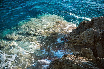 Rocky coast of the Adriatic sea. Rocks and clear sea Water. Waves break on the shore. Bright sunny day.