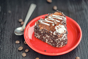 A slice of chocolate cake in the shape of a heart on a red plate.