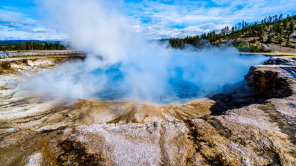 The blue-turquoise water of the Excelsior Geyser Crater in the Lower Geyser Basin at the Grand Prismatic Spring Trail in Yellowstone National Park, Wyoming, United States