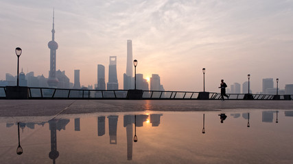 Silhouette morning runner running at famous bund zone with sun rising shanghai city background.	