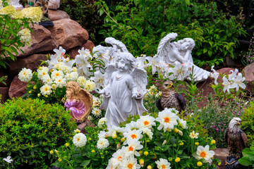 Garden statues of angels and birds on flowerbed