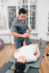 woman during exercises with her physiotherapist treating back and joint pain