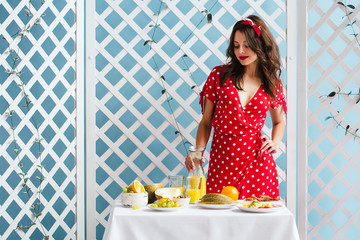 Pin-up girl in a red dress with a carafe of orange juice in her hands