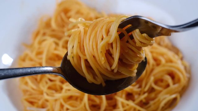 twisting fork and spoon with Italian pasta capellini closeup
