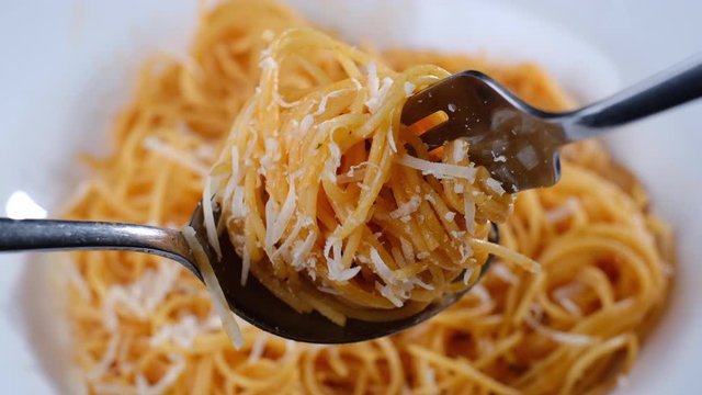 twisting fork and spoon with Italian pasta capellini and parmesan cheese closeup. Italian cuisine