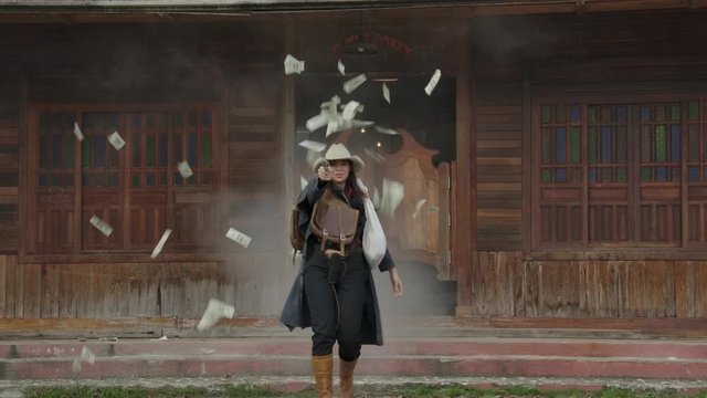 The cowgirl robber robbed the bank and walk outside of the bank she has throw the money to sky and gun shoot.