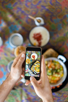 man takes a photo of food on his smartphone in the summer at a breakfast cafe. blogger food lifestyle.
