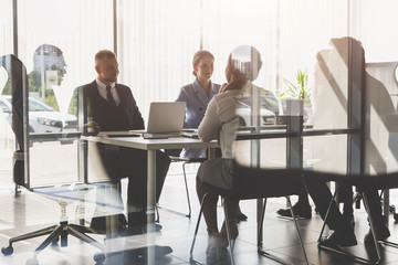 Silhouettes of people sitting at the table. A team of young businessmen working and communicating together in an office. Corporate businessteam and manager in a meeting