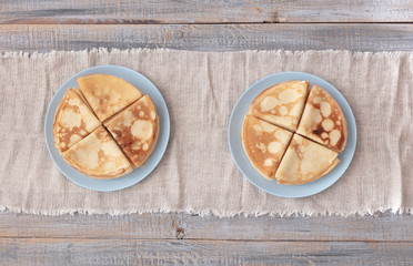 Cooking pancakes. Shrovetide (Maslenitsa) - blini stack on a blue plate on a wooden table.