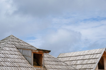 Wooden roof with cloudy sky in background.