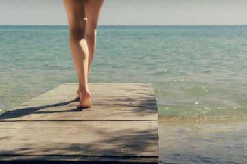 A girl walks on a bridge to the sea. The bridge on the beach. Beautiful legs and the sea.