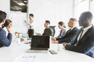 A team of young businessmen working and communicating together in an office. Corporate businessteam and manager in a meeting.