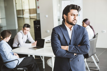 Business man stands on the background of partners. A team of young businessmen working and communicating together in an office. Corporate businessteam and manager in a meeting.