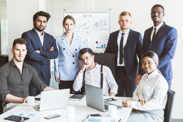 A team of young businessmen stand shoulder to shoulder, working and communicating together in an office. Corporate businessteam and manager in a meeting.