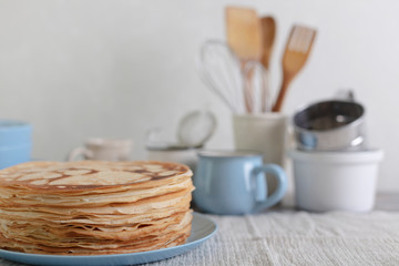 Cooking pancakes. Shrovetide (Maslenitsa) - blini stack on a blue plate on a wooden table.