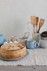 Cooking pancakes. Shrovetide (Maslenitsa) - blini stack on a blue plate on a wooden table.