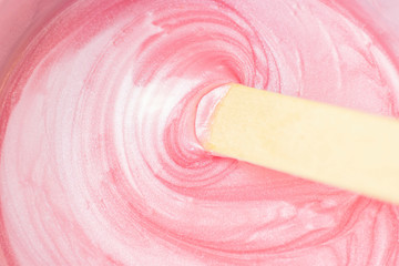 background texture liquid wax for depilation of pink color with mother of pearl with a stick. The...