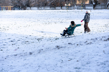 Fototapeta na wymiar Little boy and girl sledding